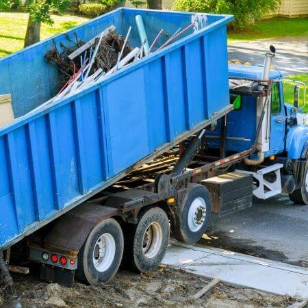 Dumpster Truck A roll-off dumpster truck is parked on the roadside, ready for waste collection and disposal services.